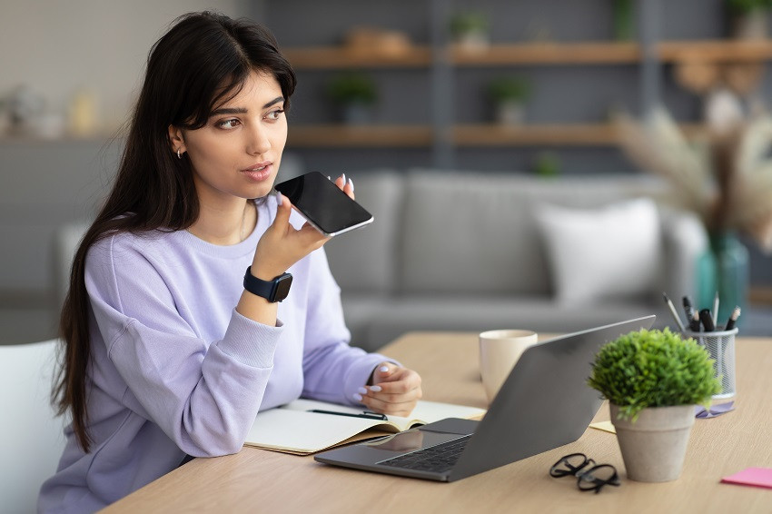 Mujer haciendo uso de aparatos tecnológicos como teléfono y computadora